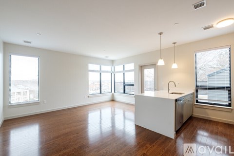 A spacious kitchen and living room with hardwood floors and large windows.