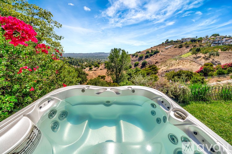 A hot tub is in the foreground with a beautiful landscape in the background.