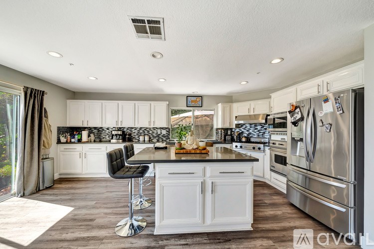 A modern kitchen with white cabinets and stainless steel appliances.