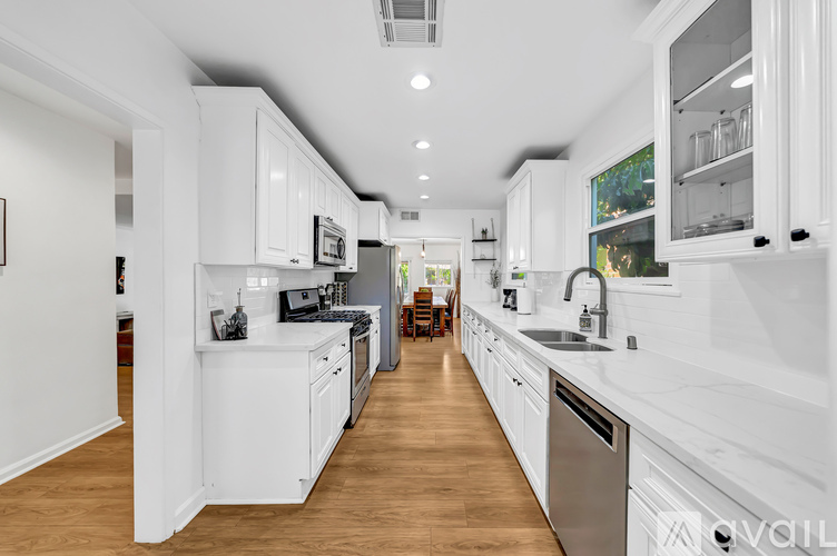 A modern kitchen with white cabinets and stainless steel appliances.