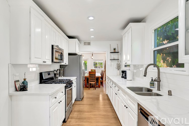 A modern kitchen with white cabinets and a wooden floor.
