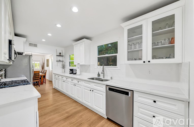 A modern kitchen with white cabinets and stainless steel appliances.