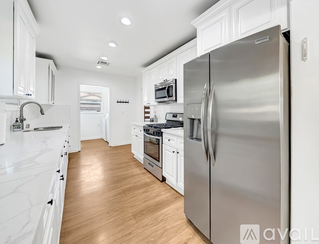 A modern kitchen with a stainless steel refrigerator and white cabinets.