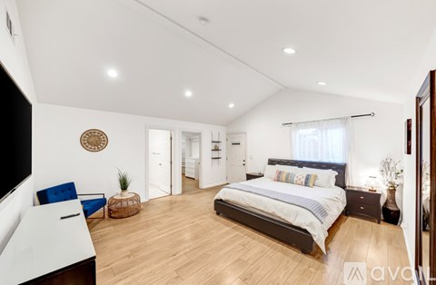 A bedroom with a large bed and a blue chair.
