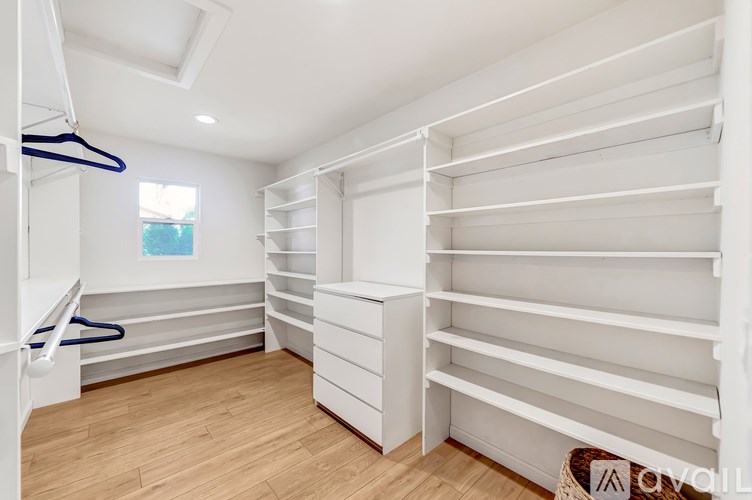 A white walk-in closet with shelves and a window.
