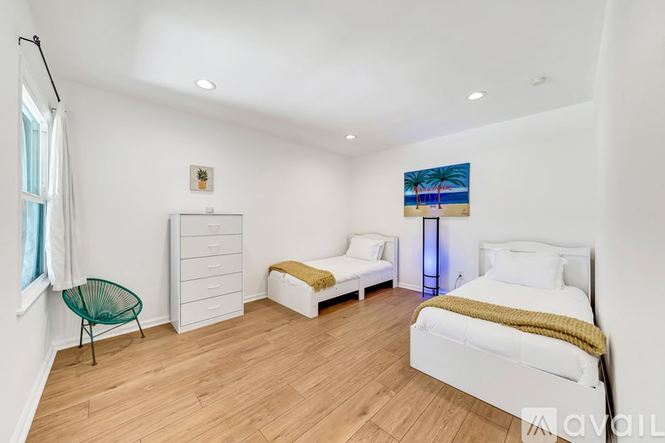 A bedroom with a white bed, a white dresser, and a white chair.