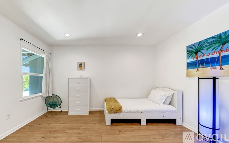 A bedroom with a bed, dresser, and chair.