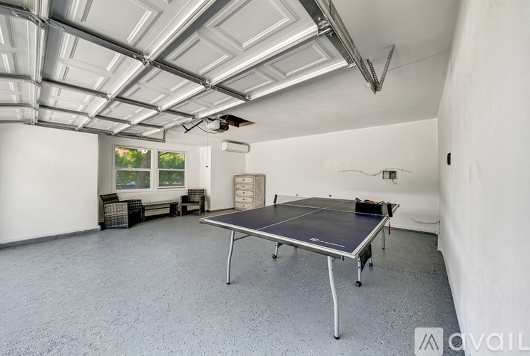 A room with a ping pong table and a ceiling fan.