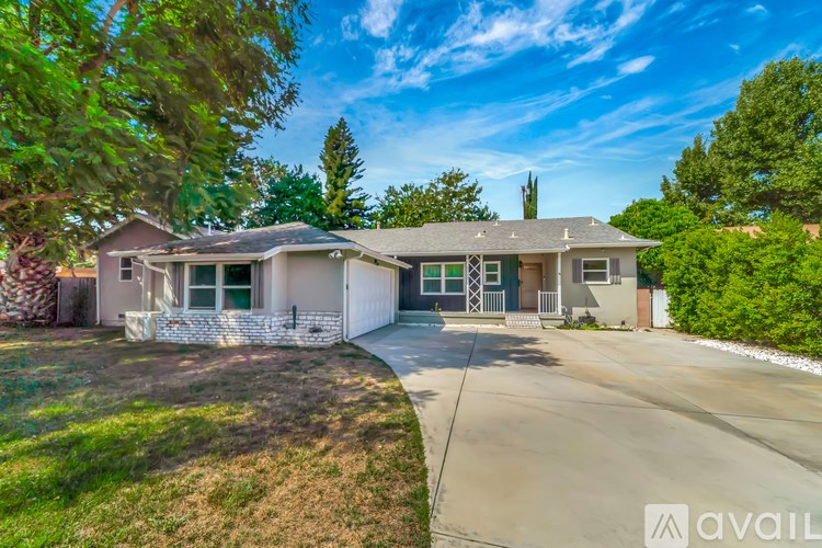 A house with a driveway and a tree in front of it.