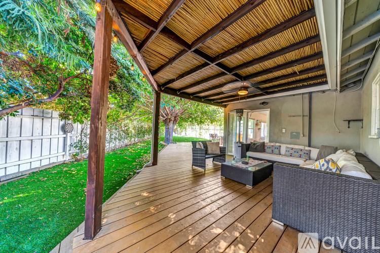A wooden deck with a couch and a table under a roof.