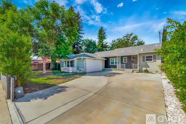 A house with a driveway and trees in front.
