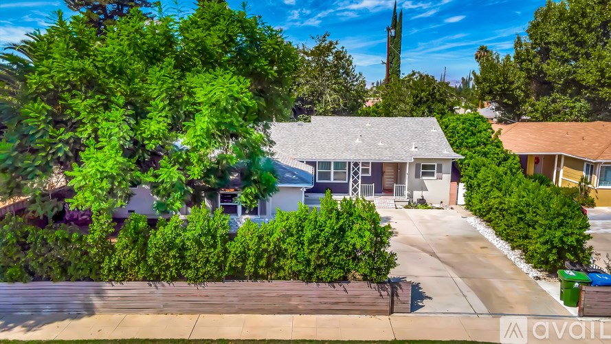 A house with a driveway and a tree in front of it.