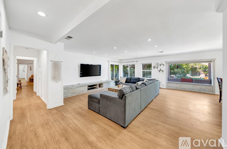A spacious living room with a grey sofa and wooden flooring.