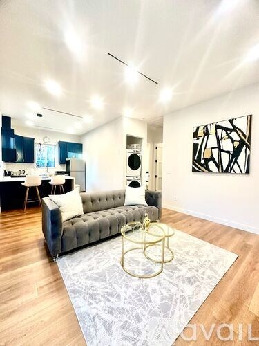 A living room with a grey sofa and a large abstract painting on the wall.