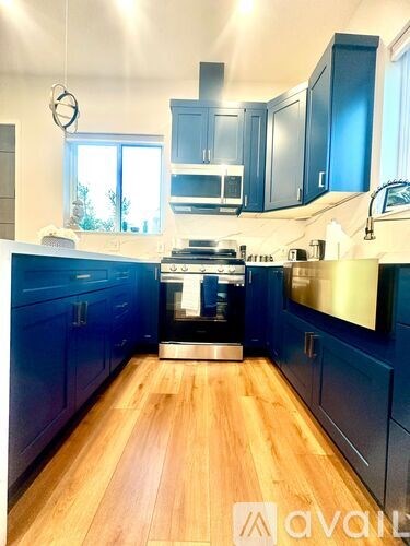 A kitchen with dark blue cabinets and a wooden floor.