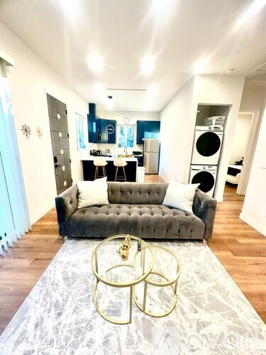 A living room with a grey couch and a white rug.