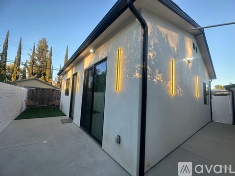 A modern house with a white exterior and a black roof is available for rent.