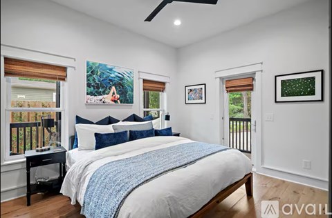 A bedroom with a large bed and a painting of a woman on the wall.