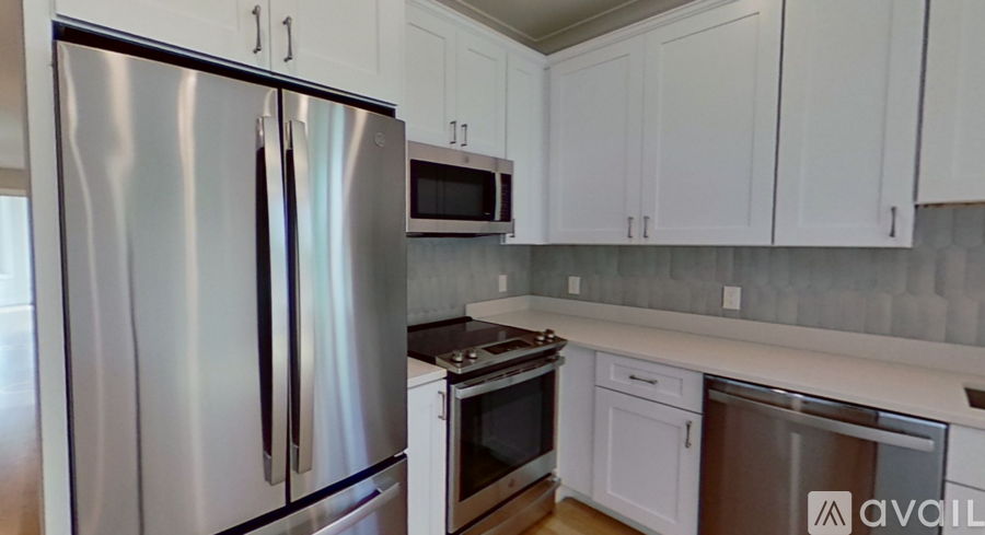 A kitchen with a stainless steel refrigerator and white cabinets.