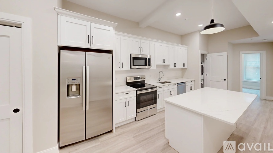 A kitchen with white cabinets and a stainless steel refrigerator.