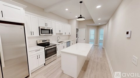 A modern kitchen with white cabinets and a wooden floor.