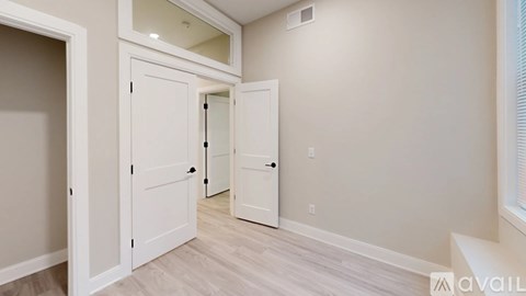 A hallway with three white doors and a wooden floor.