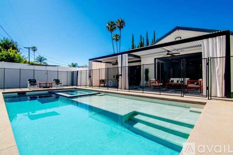 A pool with a glass barrier and a white building in the background.