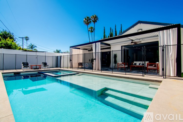 A pool with a glass barrier and a white building in the background.
