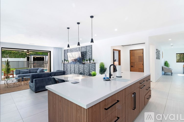 A modern kitchen with a large island and a view of a greenhouse.