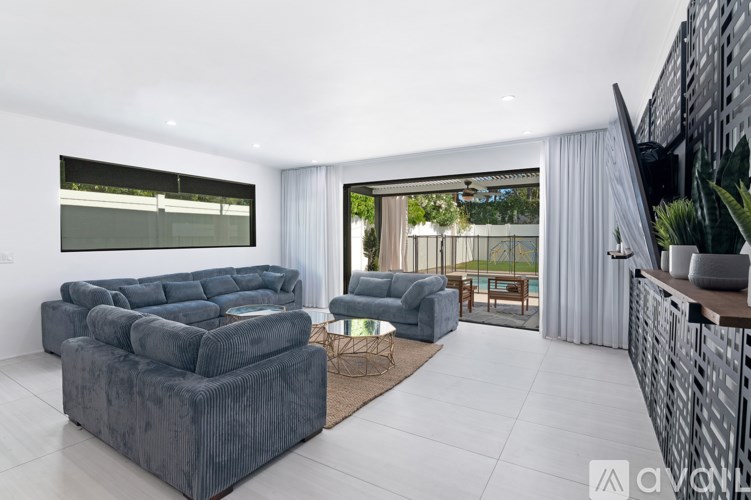 A modern living room with grey couches and a glass table.