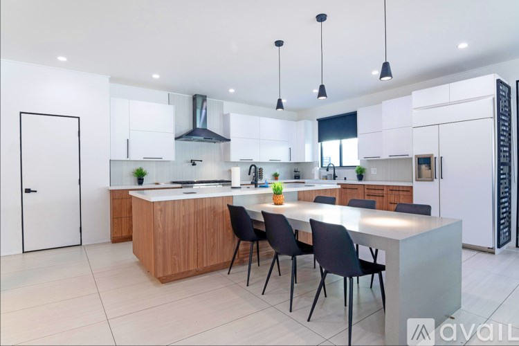 A modern kitchen with a central island and black chairs.