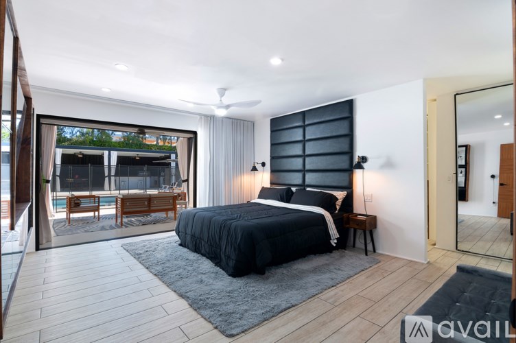 A bedroom with a large bed and a balcony overlooking the pool.