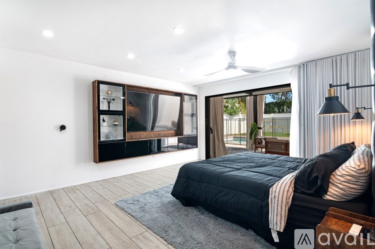 A bedroom with a large bed and a sliding glass door leading to a balcony.