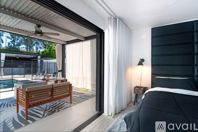 A modern bedroom with a large bed and a patio area.