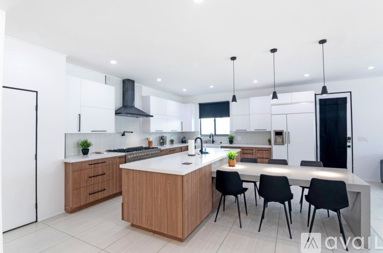 A modern kitchen with a large island and black chairs.