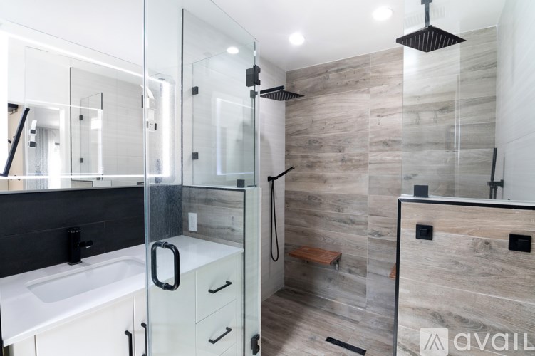 A modern bathroom with a walk-in shower and a white sink.