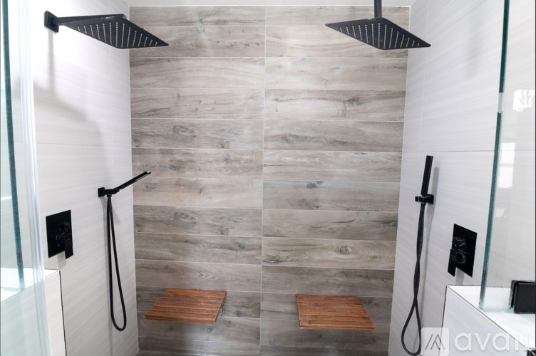 A modern bathroom with a walk-in shower and wooden flooring.