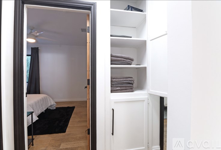 A small bedroom with a bed and a cabinet with towels.