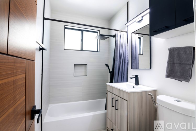 A modern bathroom with a white tub, sink, and a window.