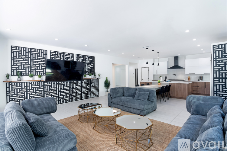 A living room with a grey couch and a TV mounted on the wall.