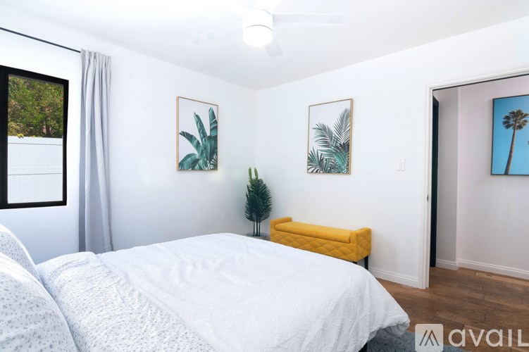 A bedroom with a white bed and a yellow bench.