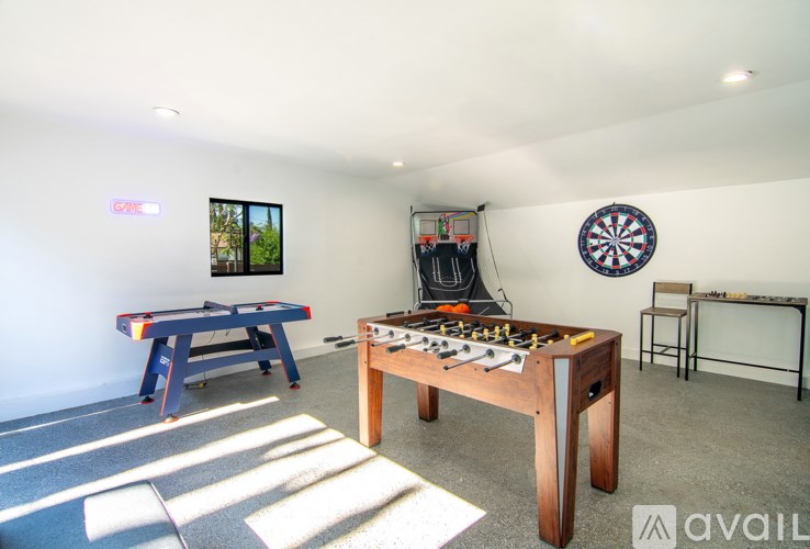 A room with a foosball table, air hockey table, and a dartboard.