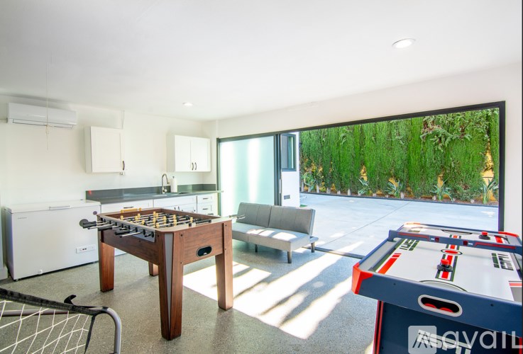 A foosball table is in the middle of a room with a couch and a dining table.