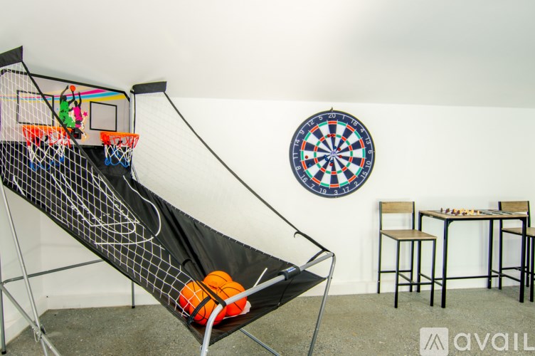 A room with a dartboard, a slide, and a table with chairs.