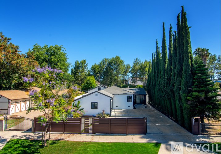 A white house with a brown gate and a green lawn.
