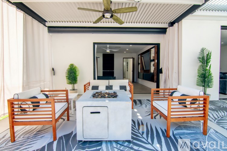 A patio with a white table and chairs, a fireplace, and a ceiling fan.