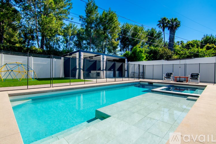 A pool surrounded by a fence with a sunny sky in the background.