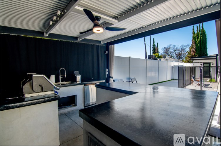 A modern kitchen with a black countertop and a ceiling fan.