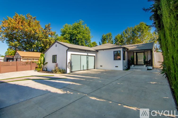 A modern house with a large driveway and a clear blue sky above.