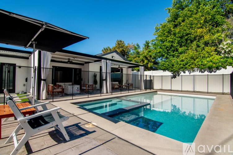 A pool in a backyard with a white chair and a white house.